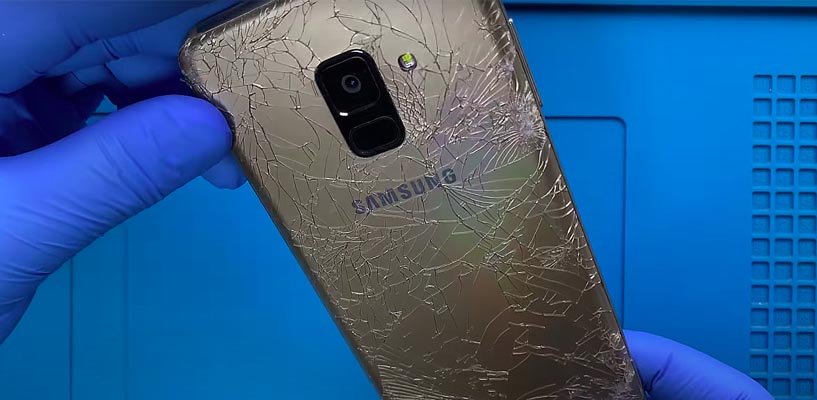 Сильно разбитая задняя крышка телефона samsung A8 в руках мастера