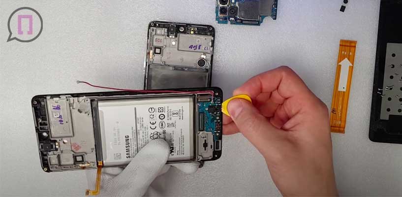 Специалист поддевает материнскую плату и извлекает ее из корпуса samsung M51