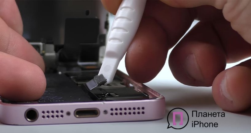 Мастер аккуратно снимает батарею iPhone SE